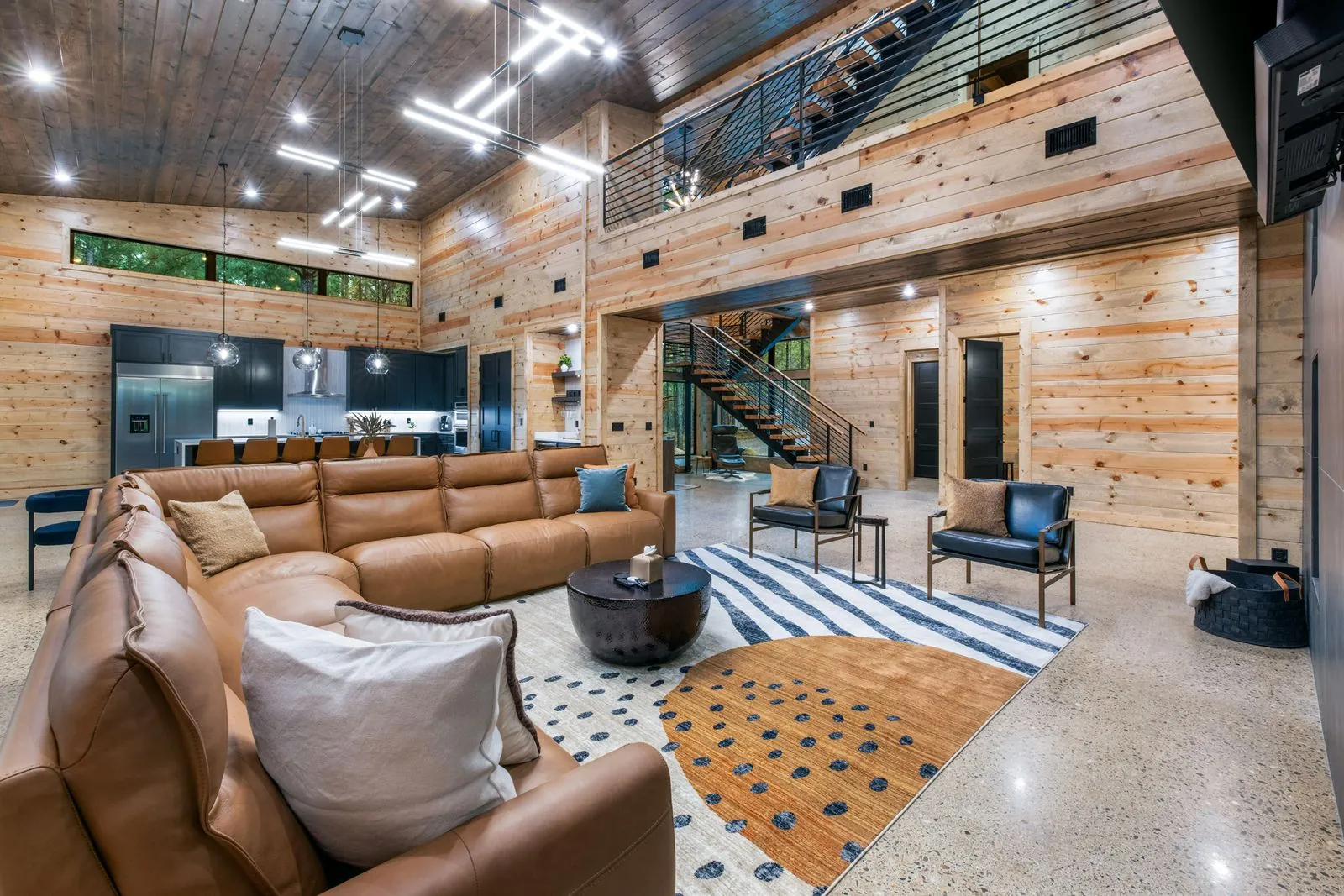 Spacious living area at LivNLove featuring dual leather sectional sofas, linear fireplace, and wood-paneled vaulted ceiling