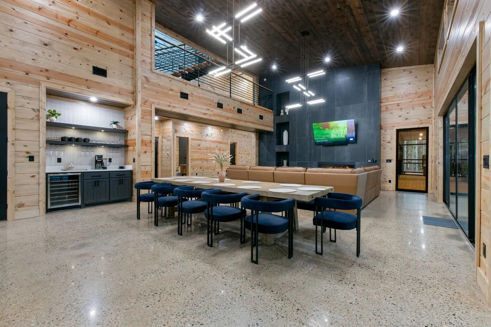 Open living and dining space at LivNLove with cathedral wood ceiling, dramatic pendant lighting, and staircase