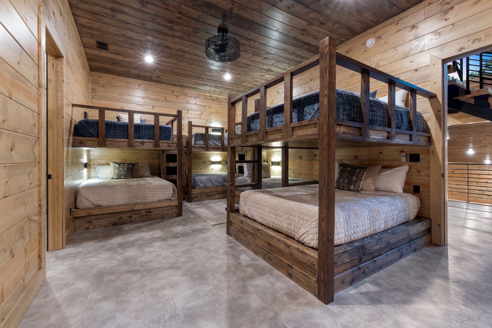 Bedroom suite at LivNLove with king bed, blue and gray bedding, dark curtains, forest view, and white pouf seating