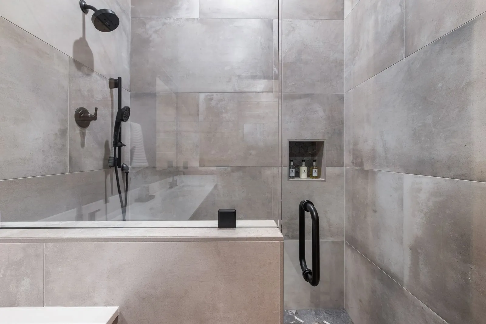 Walk-in shower with dark tile surround, rain showerhead, and frameless glass enclosure at LivNLove