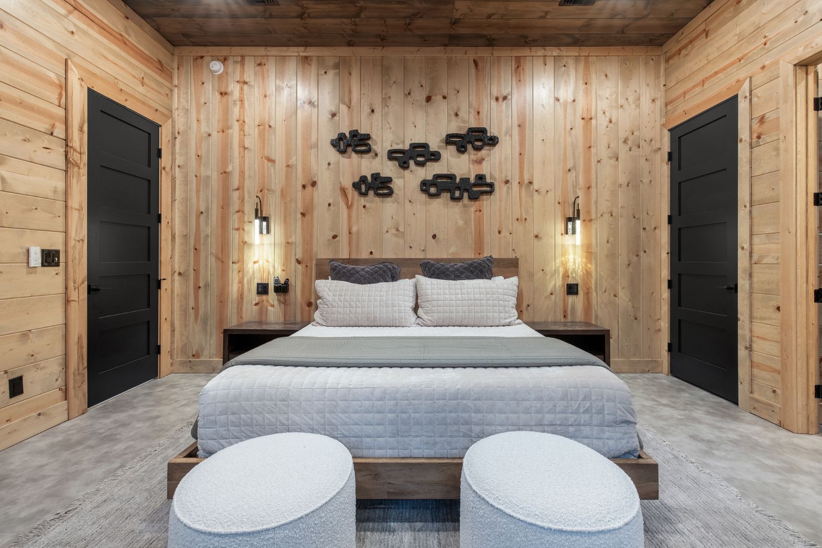 Close-up of king bed at LivNLove with white textured bedding, decorative wood mushroom wall sculptures, and sconce