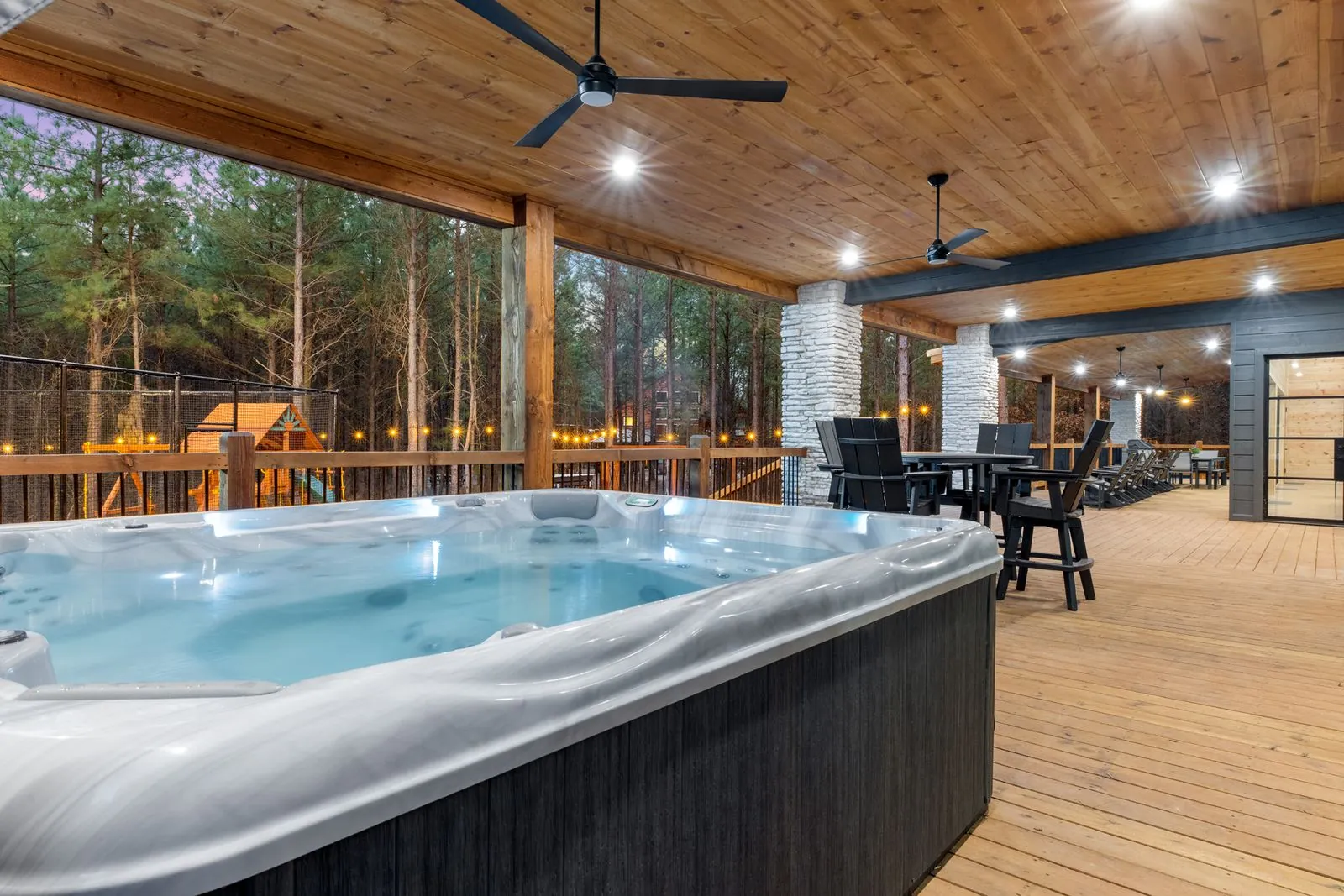 Hot tub on the covered wooden deck at LivNLove with ceiling fan and forest views