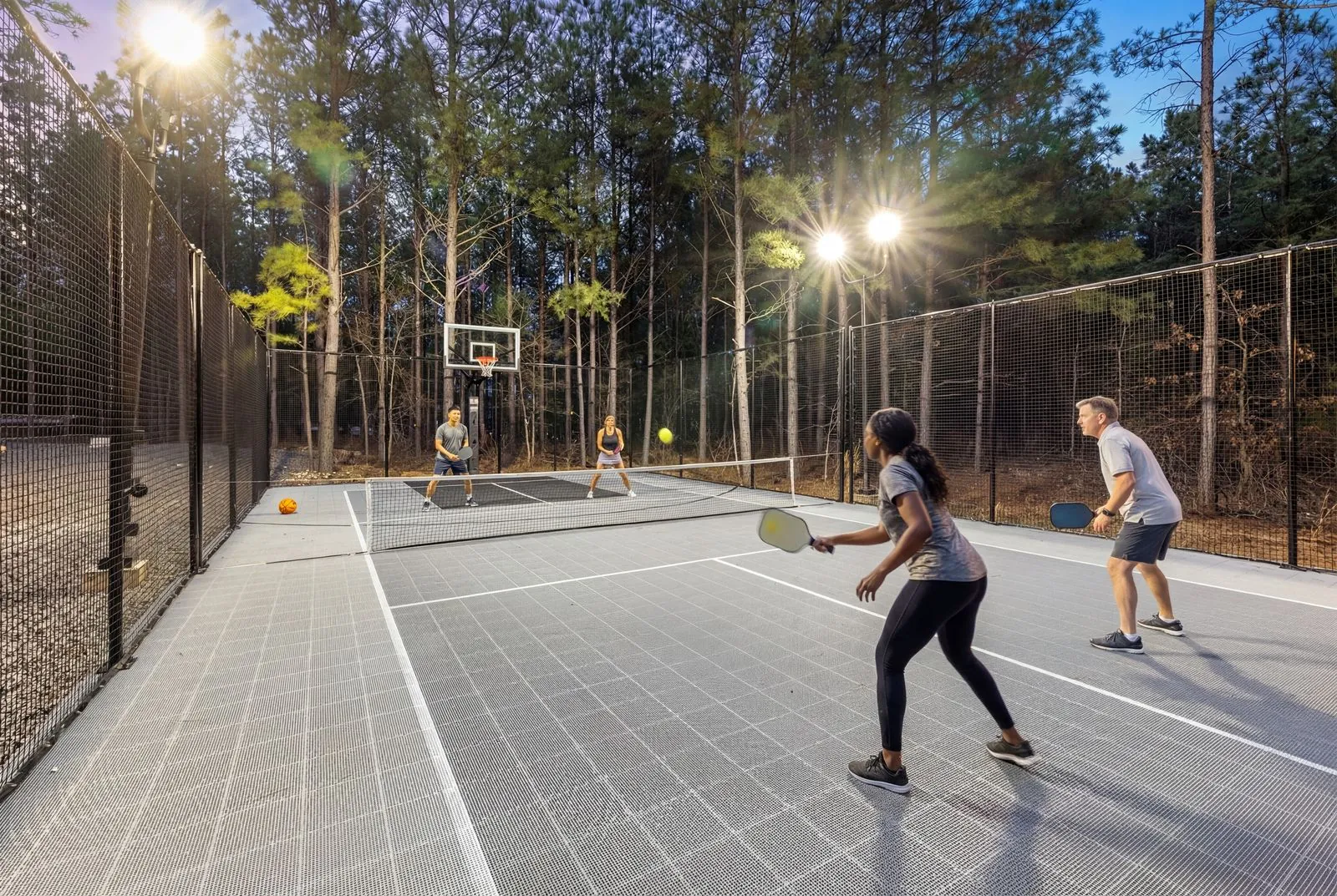 Guests playing pickleball under the lights on the private court at LivNLove at dusk