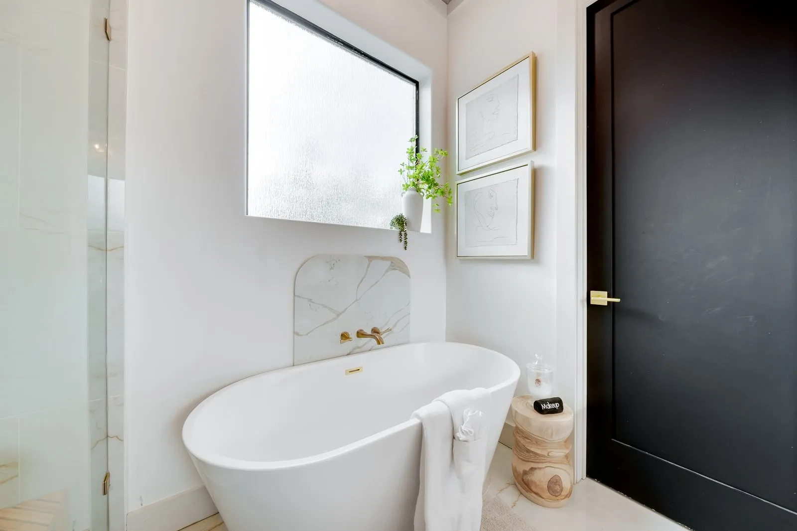 Bathroom vanity at The Malibu with dark cabinet, marble countertop, gold fixtures, and framed artwork