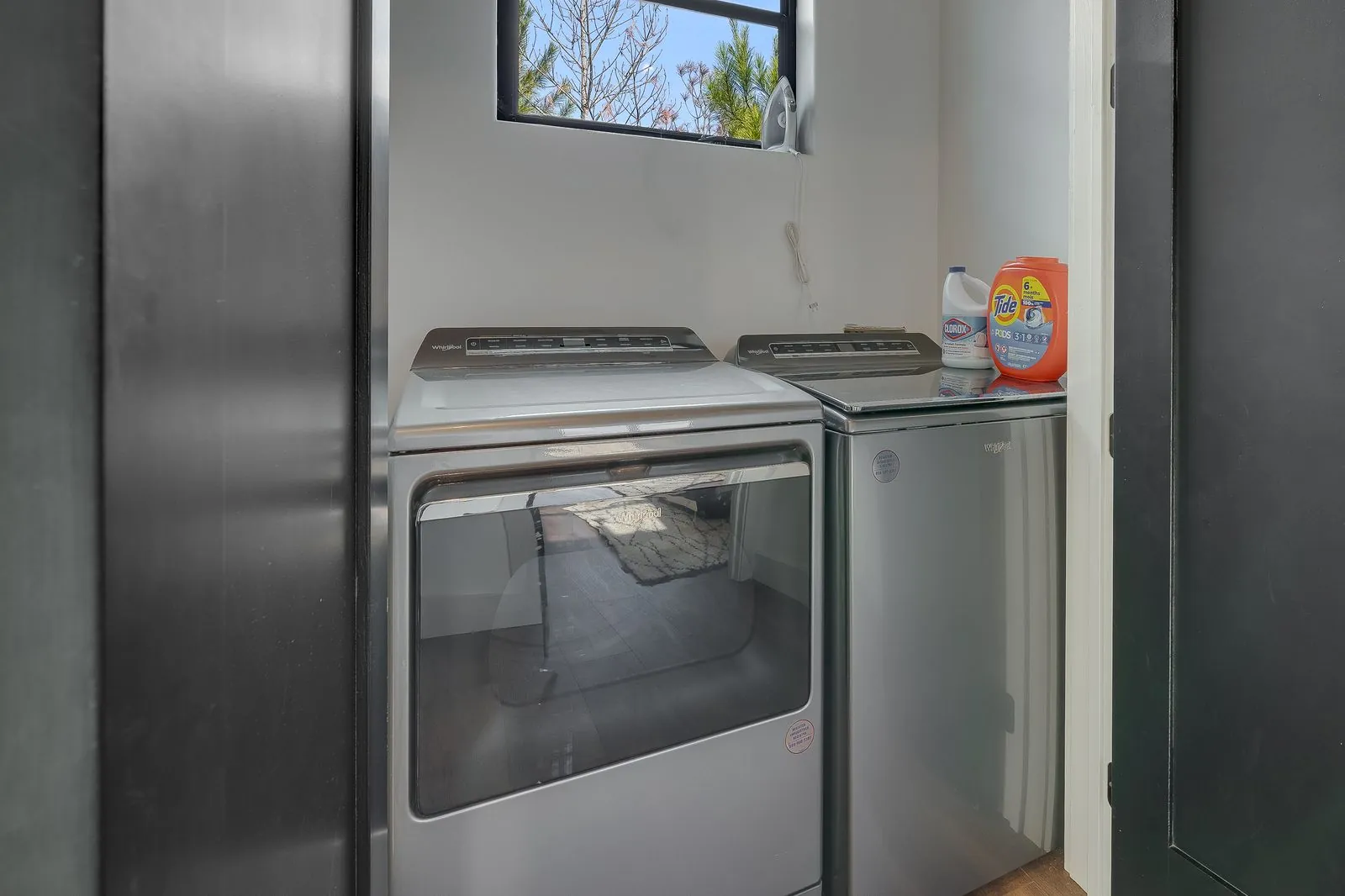 Laundry room at The Malibu with full-size washer and dryer, dark cabinetry, and window with natural light