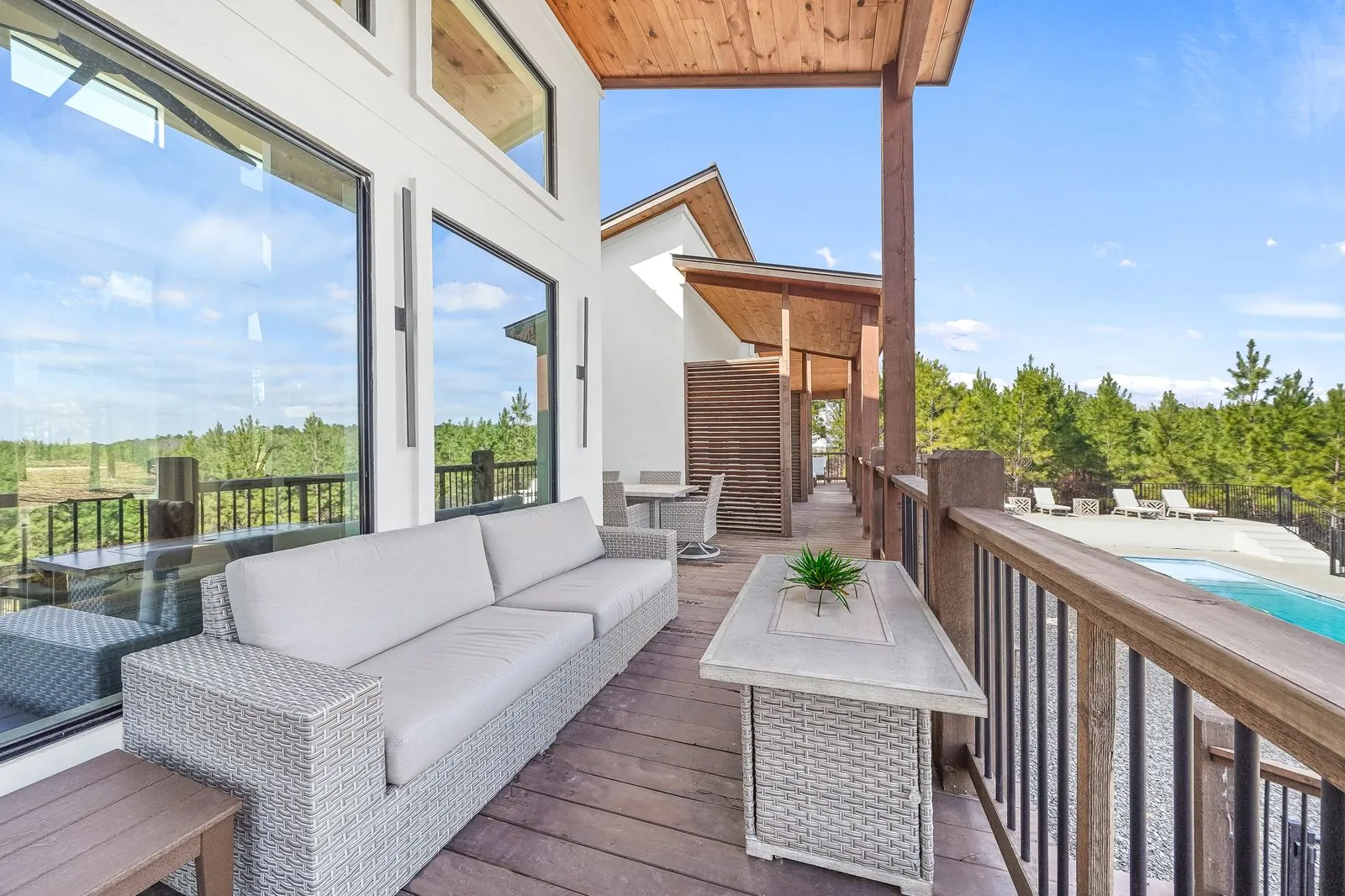 Upper covered deck at The Malibu overlooking the heated pool and Broken Bow forest with outdoor lounge seating