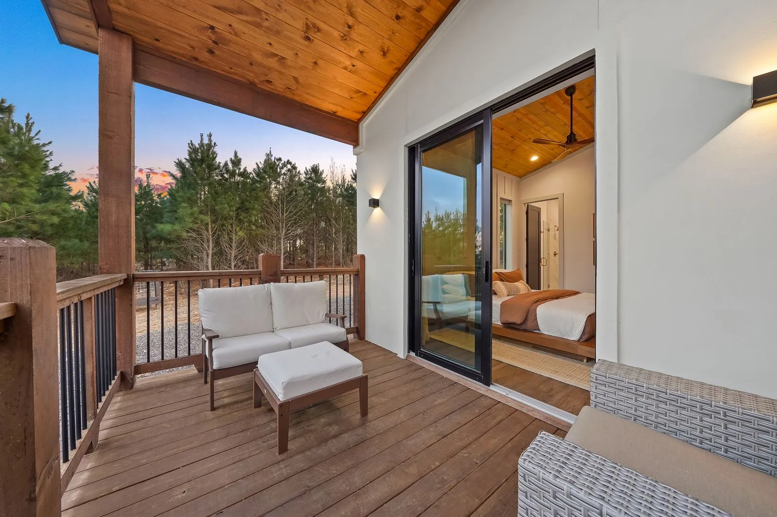 Bedroom at The Malibu with king bed, forest view through sliding glass doors, and private balcony access