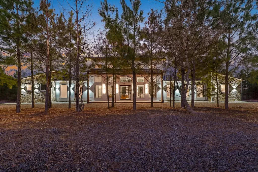 Wide front exterior of The Malibu through pine trees at blue hour