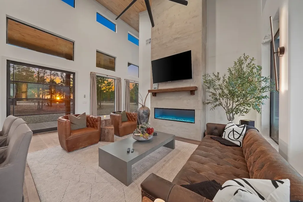Living room seating around the linear fireplace beneath tall windows