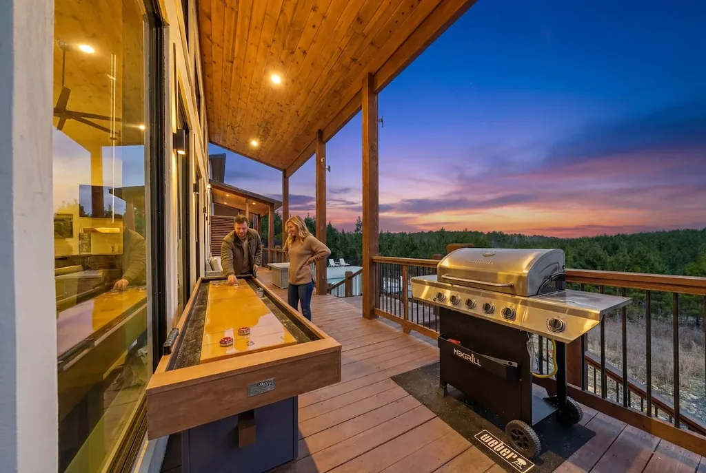 Covered deck with shuffleboard table, stainless grill, and sunset view