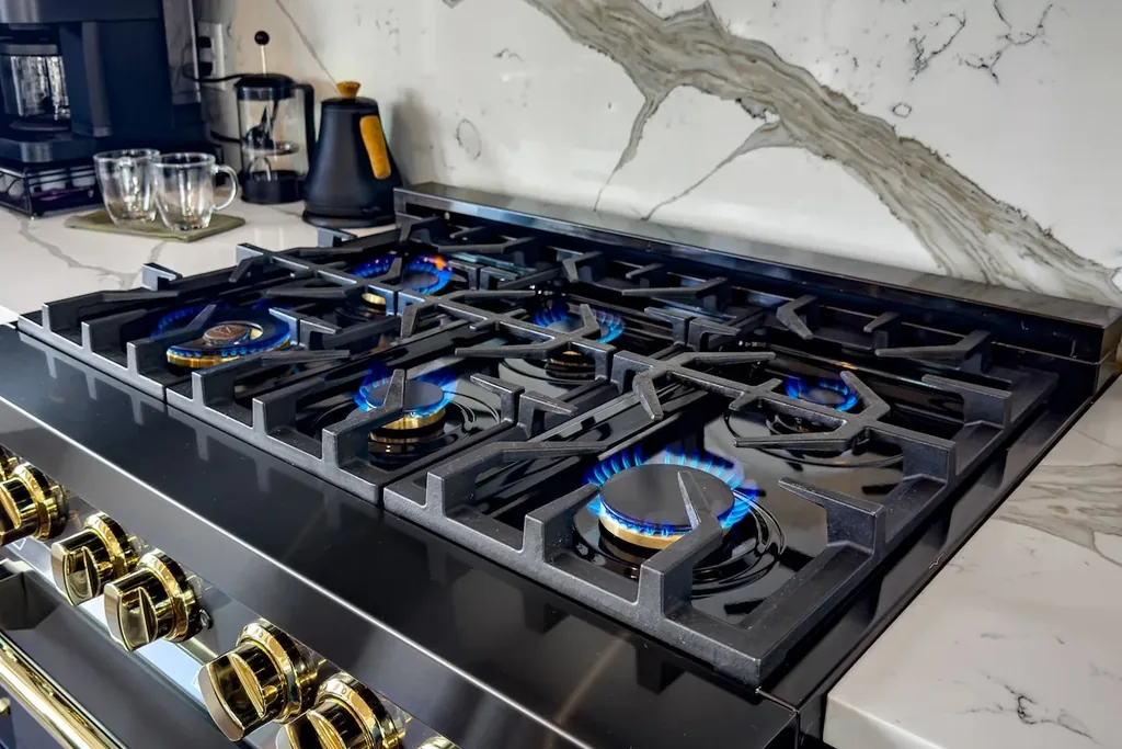 Gas cooktop with blue flames and black-and-gold controls
