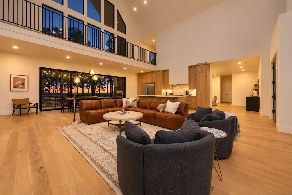 Sanctuary at the Summit — Floor-to-ceiling windows frame a sunset view behind a leather sectional, anchoring a living room built for gathering.